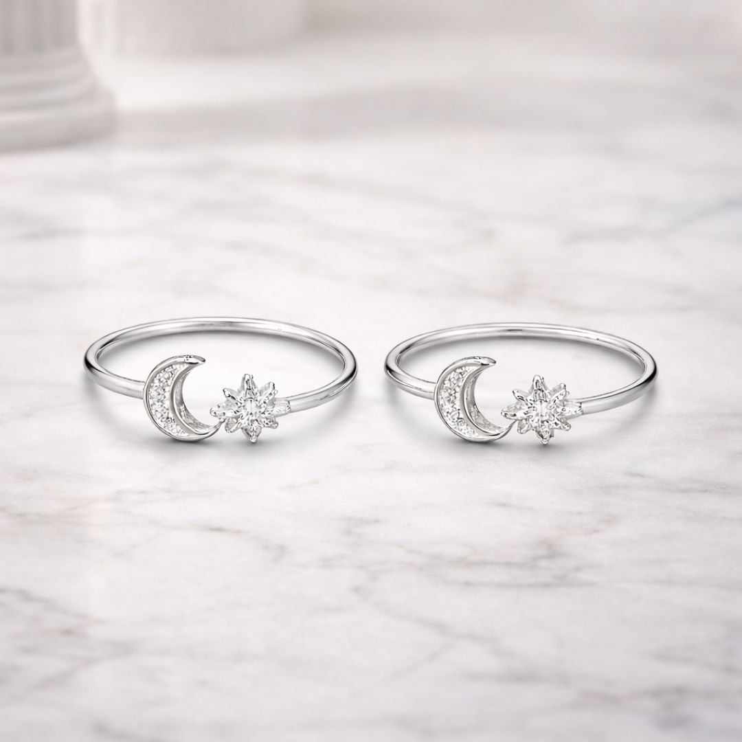 Pair of silver rings with moon and star designs on a marble surface