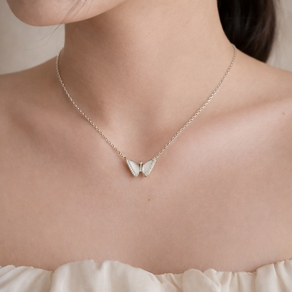 Silver butterfly necklace on a person wearing a white top