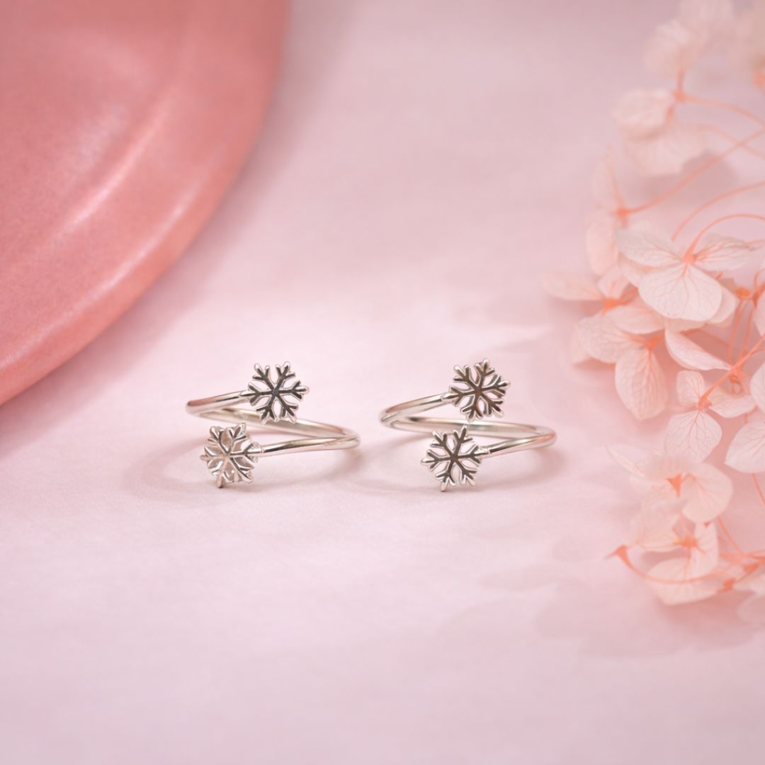 Silver snowflake rings on a pink surface with flowers