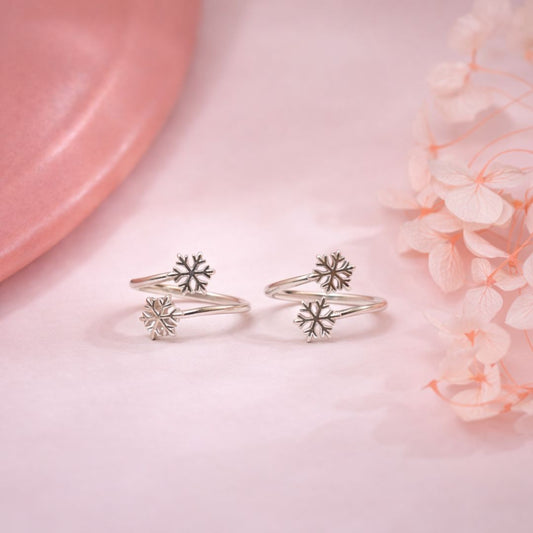 Silver snowflake rings on a pink surface with flowers
