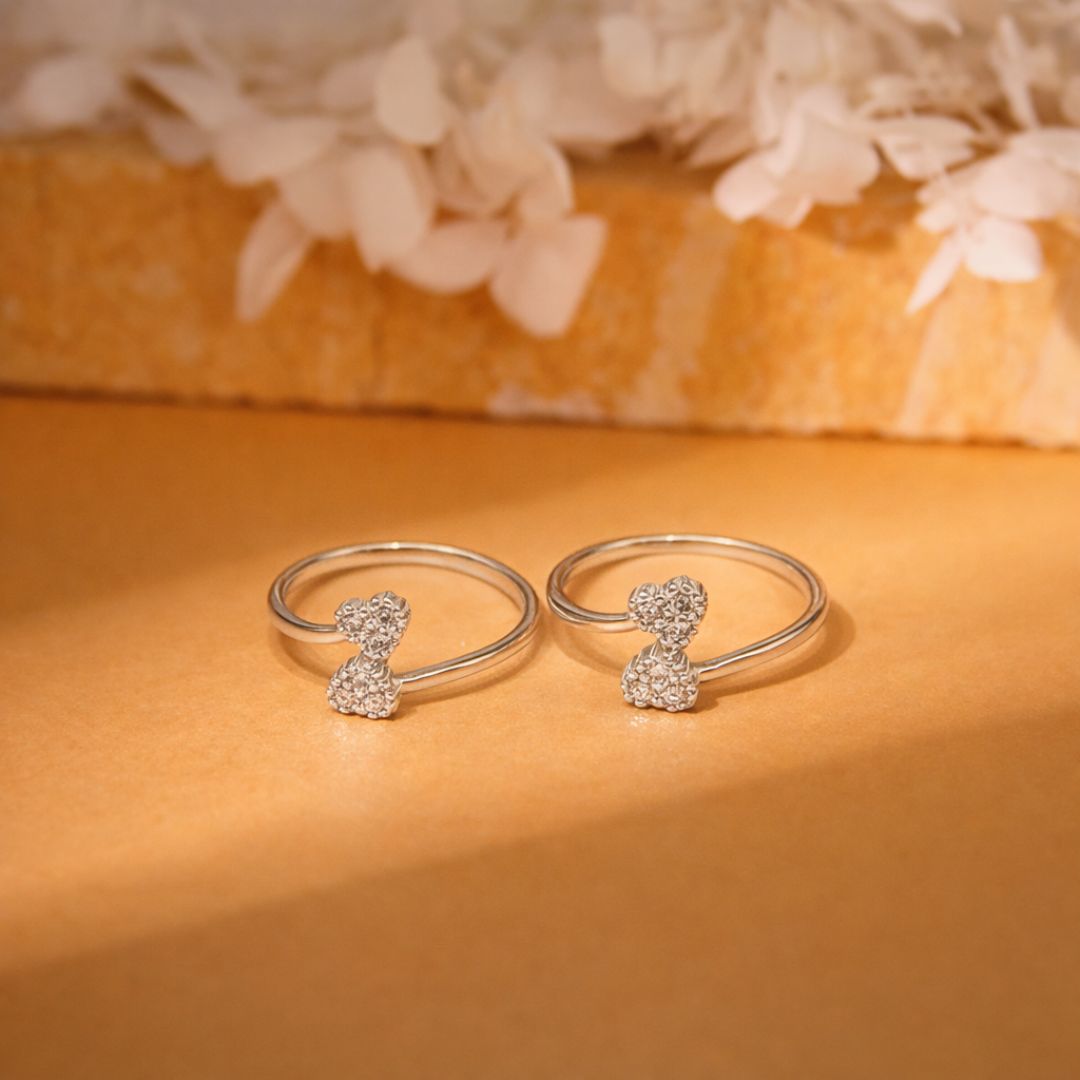 Two silver rings with small decorative elements on a warm-toned surface.