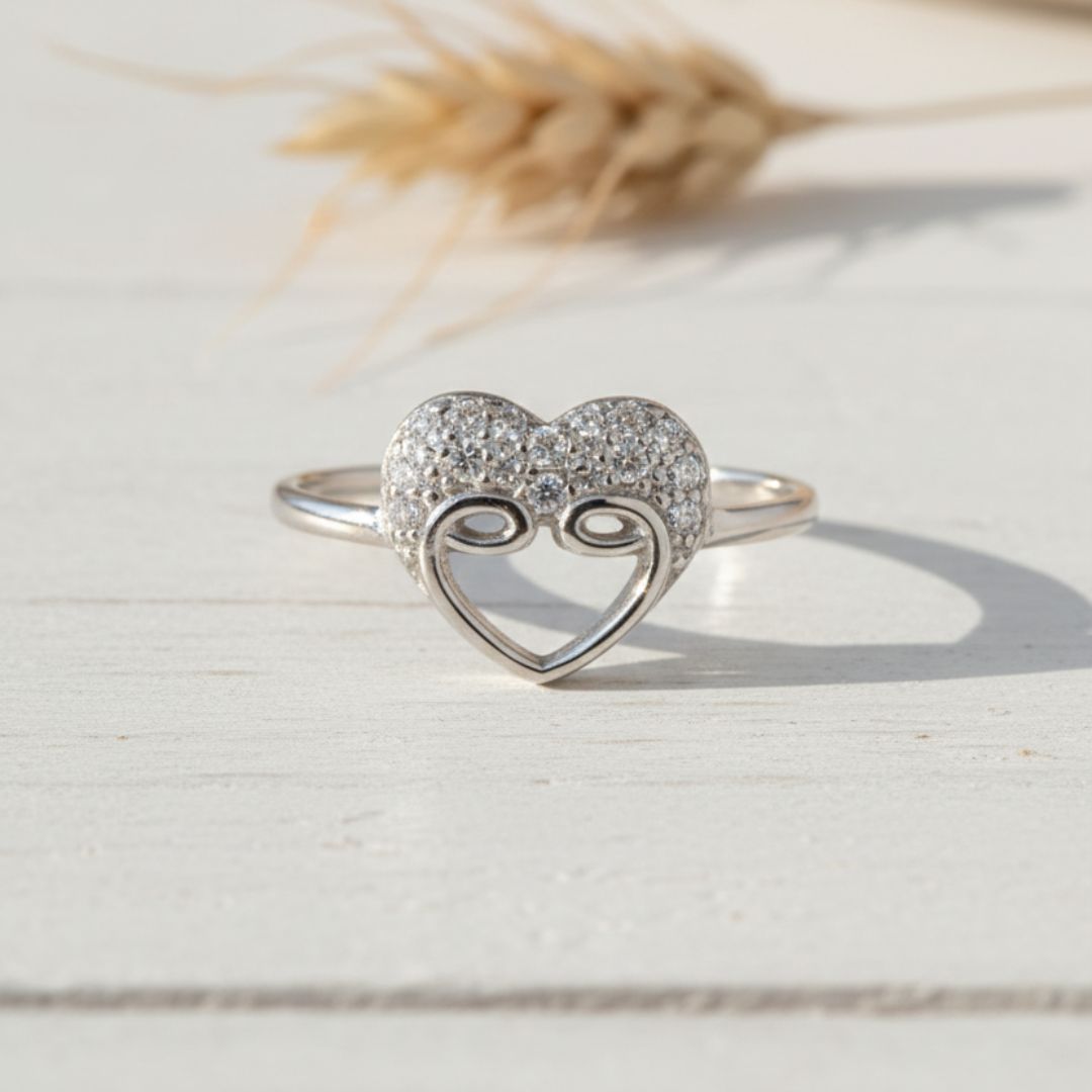 Silver ring with heart design on a light wooden surface