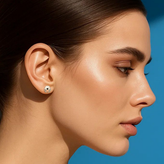 Woman with a ponytail wearing earrings against a blue background