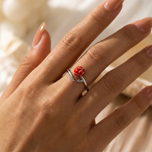 Hand wearing a silver ring with a red gemstone against a blurred background