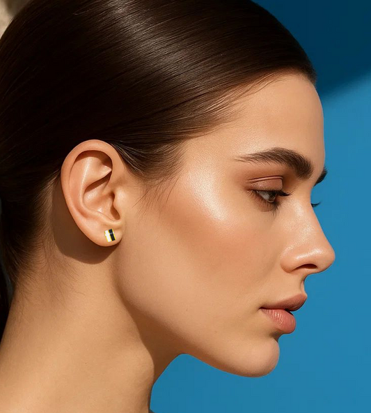 Woman with a ponytail wearing an earring against a blue background.