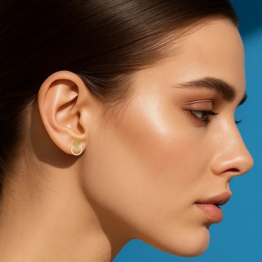 Woman with a ponytail wearing earrings against a blue background
