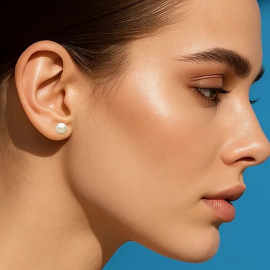 Woman wearing a pearl earring against a blue background.