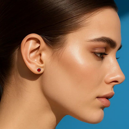 Woman with a ponytail wearing a red earring against a blue background