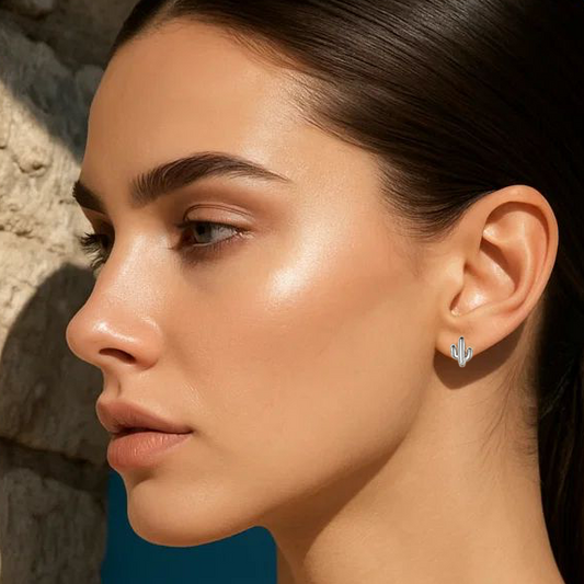 Woman with a ponytail wearing earrings against a blue background