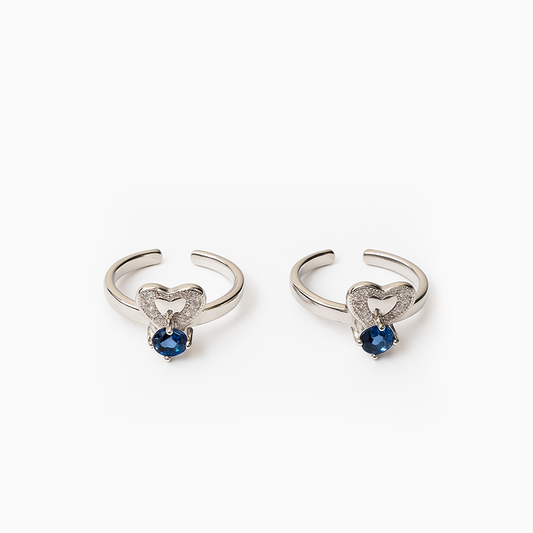 Pair of silver heart-shaped earrings with blue gemstones on a white background