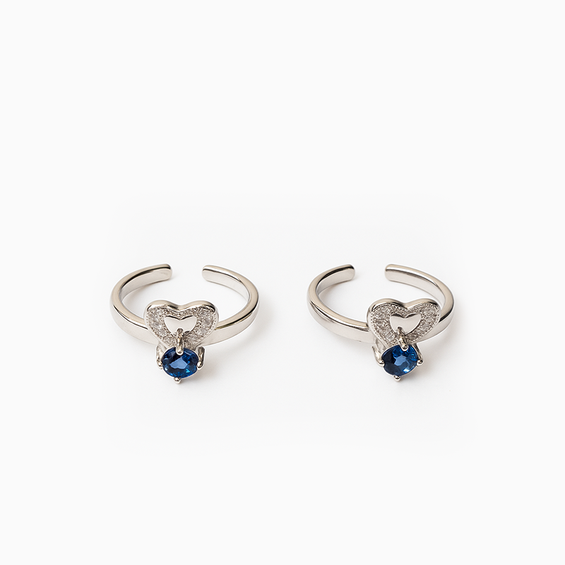 Pair of silver heart-shaped earrings with blue gemstones on a white background