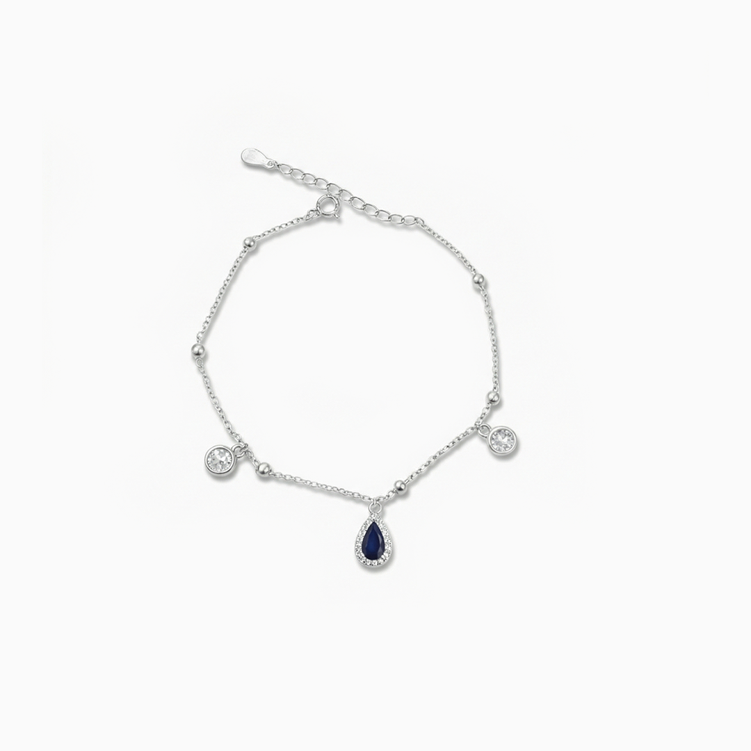 Silver bracelet with teardrop-shaped blue gemstone on a white background