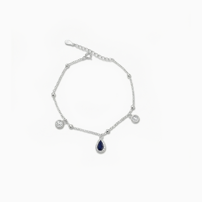 Silver bracelet with teardrop-shaped blue gemstone on a white background