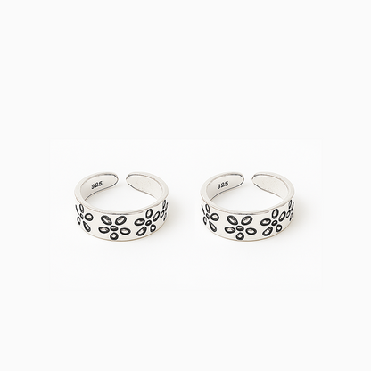 Two silver open rings with floral patterns on a white background