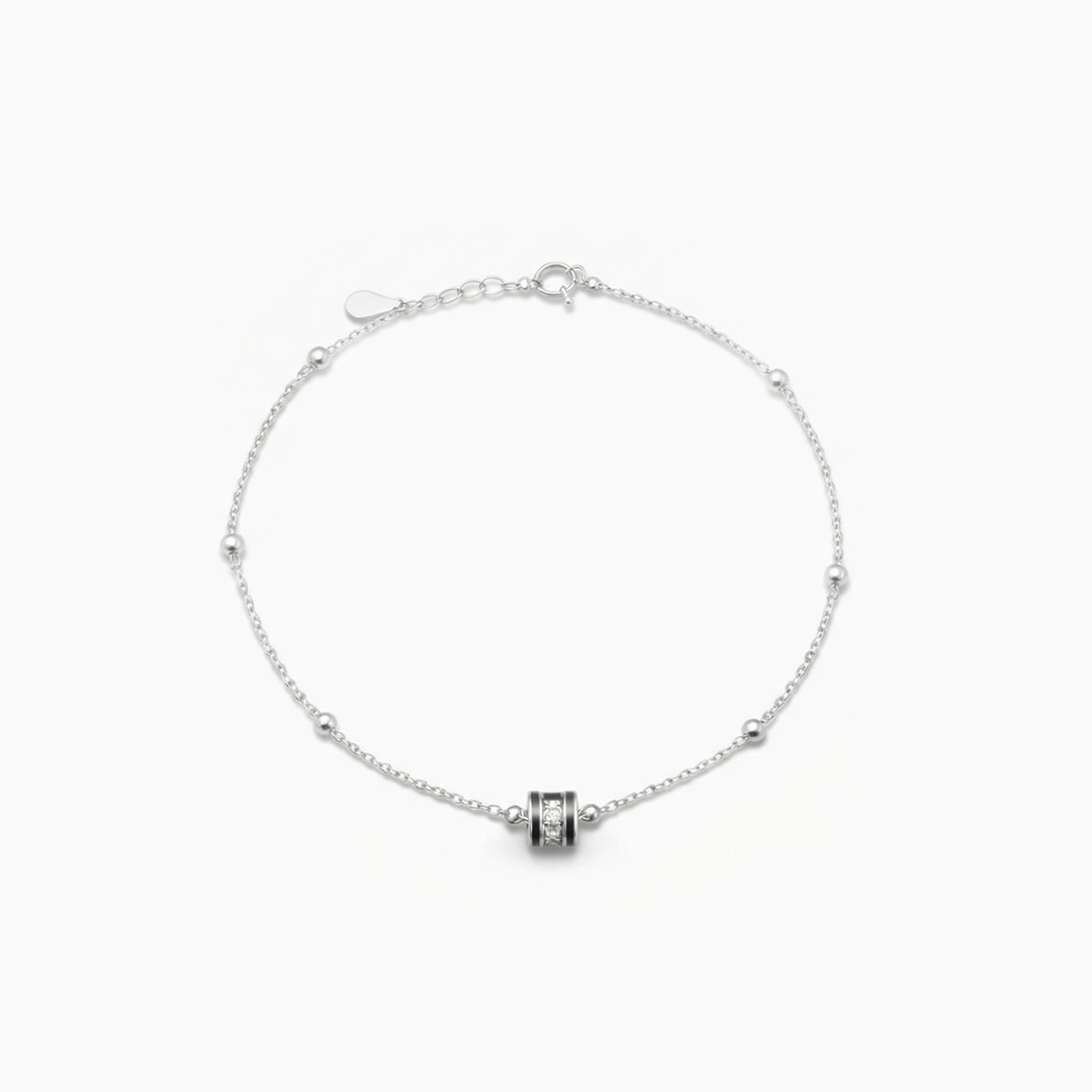 Silver bracelet with a cylindrical charm on a white background