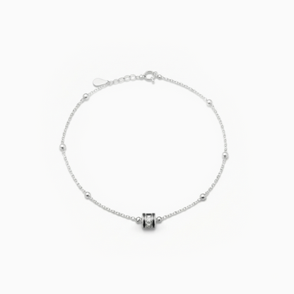 Silver bracelet with a cylindrical charm on a white background