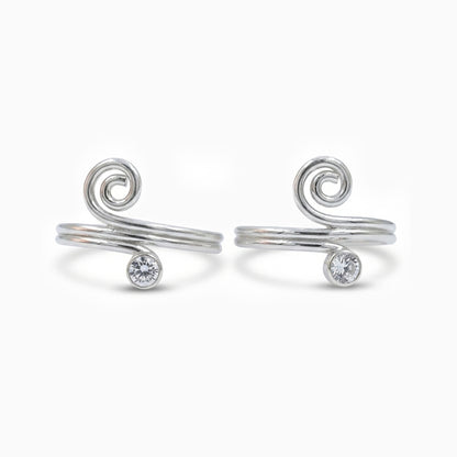 Pair of silver spiral toe rings with small gemstones on a white background