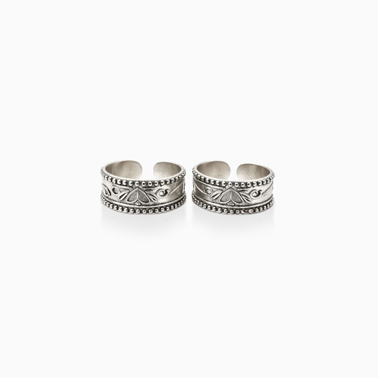 Two silver toe rings with intricate designs on a white background