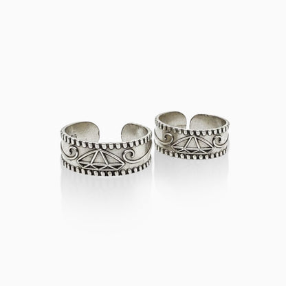 Two silver toe rings with intricate designs on a white background