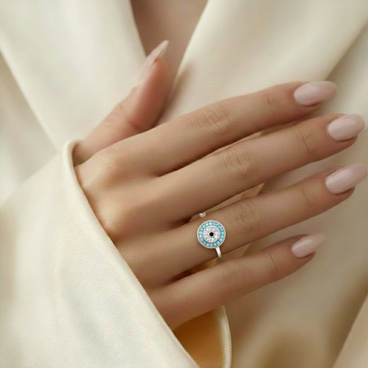Hand wearing a silver ring with a blue gemstone on a light background