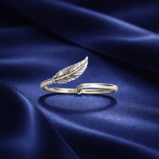 Silver feather-shaped ring on a blue satin background