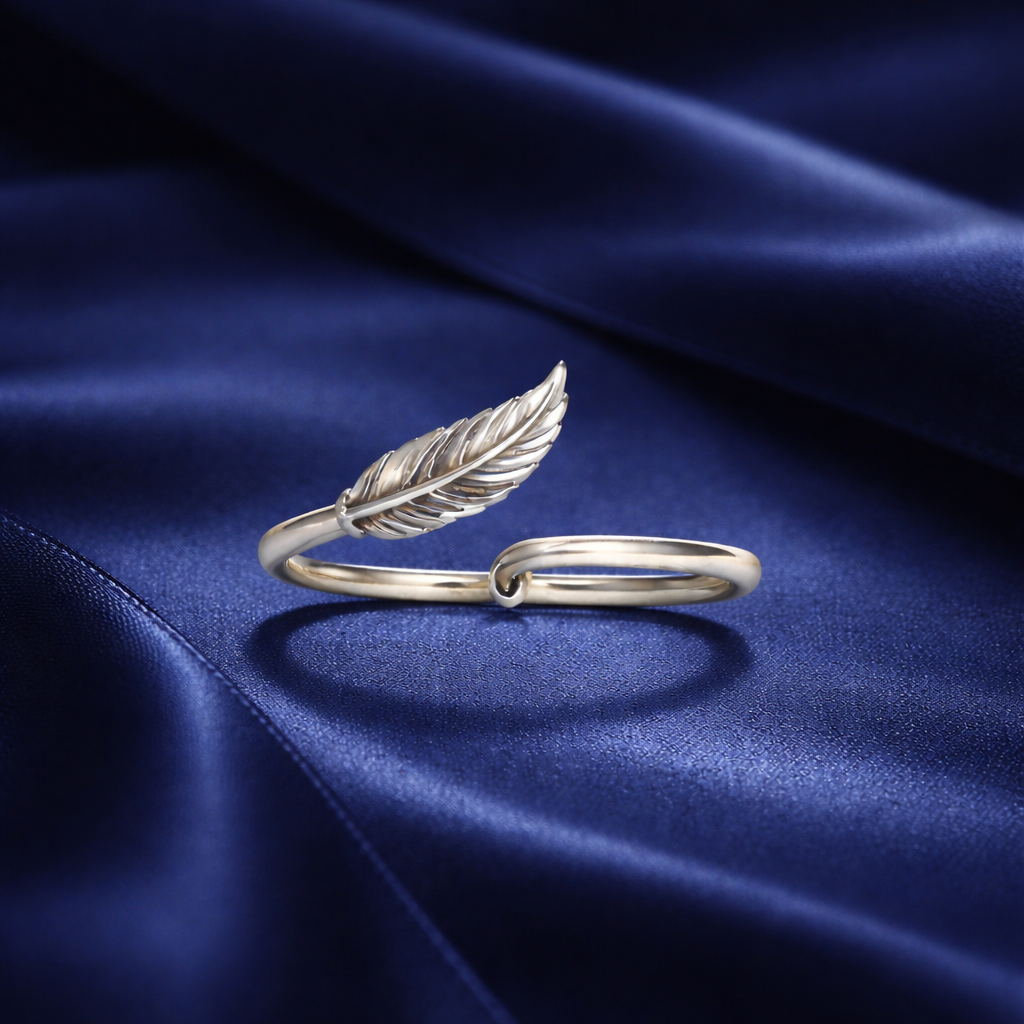 Silver feather-shaped ring on a blue satin background