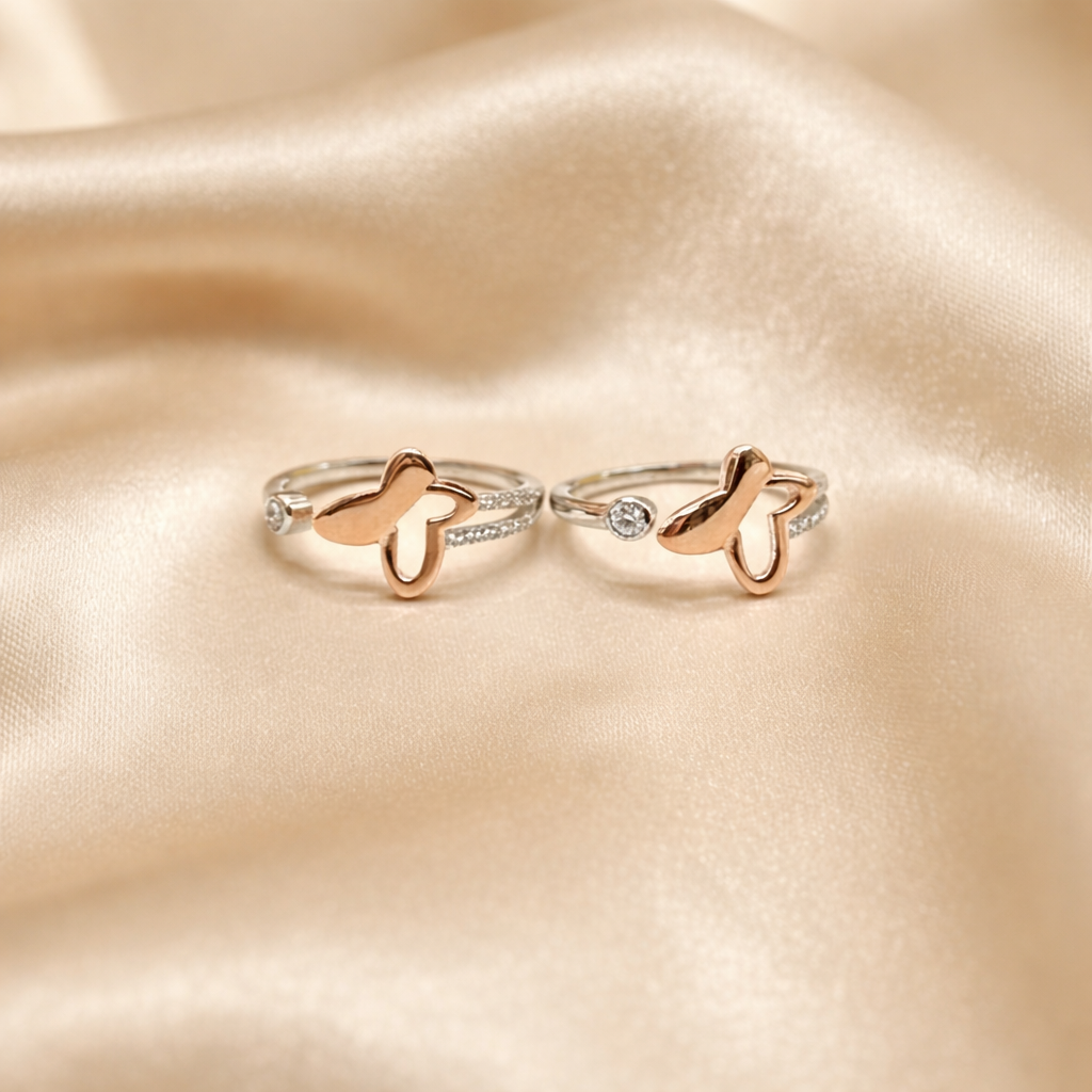 Two butterfly-shaped toe rings on a soft beige fabric background