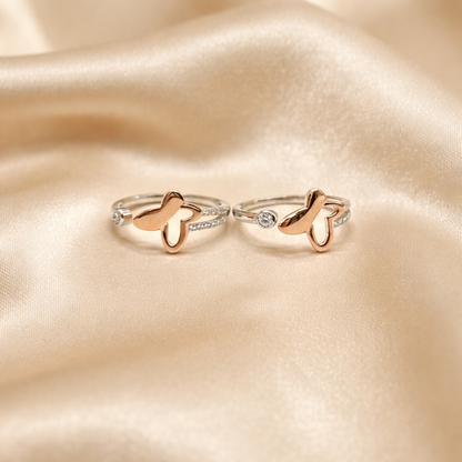 Two butterfly-shaped toe rings on a soft beige fabric background