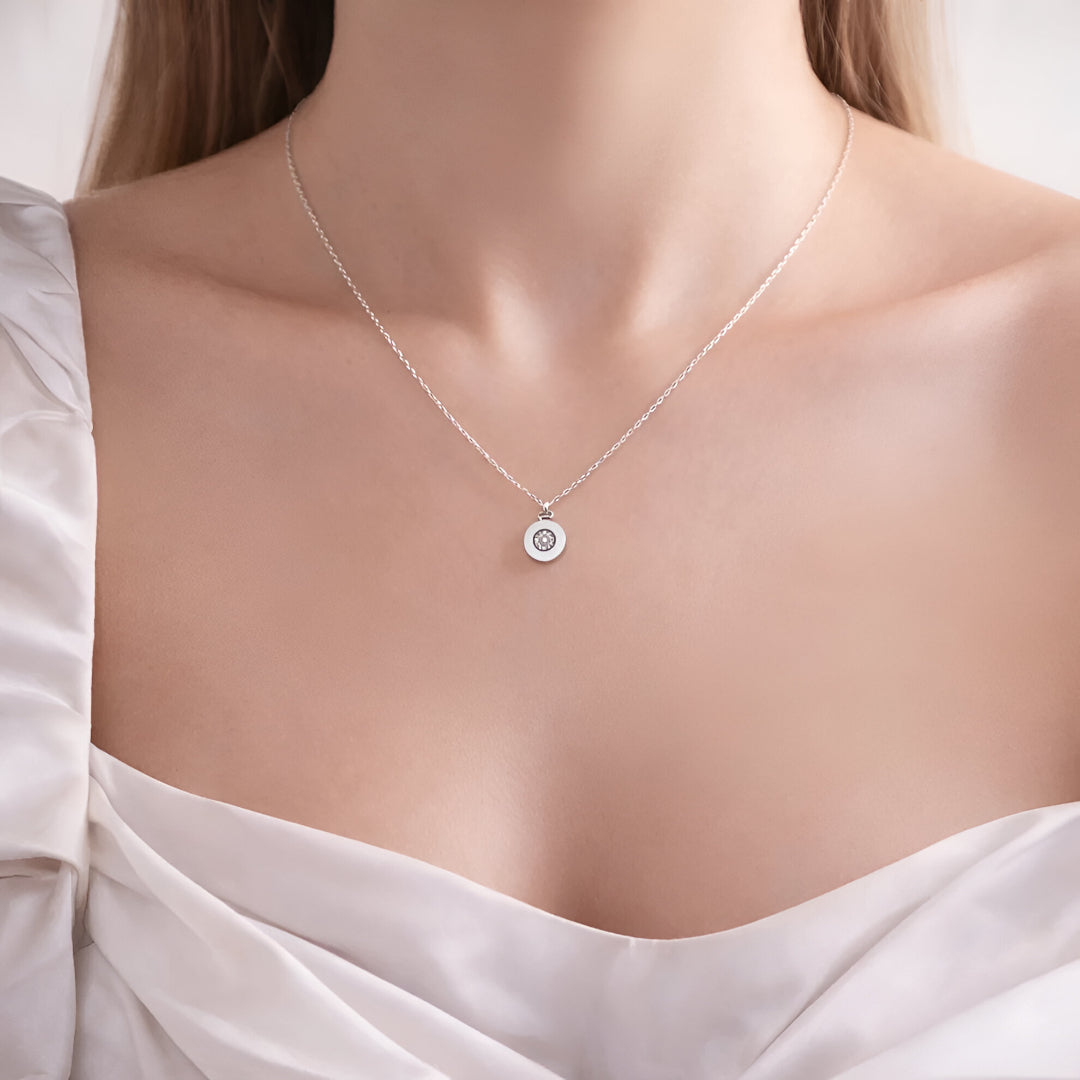 Necklace with a circular pendant on a mannequin wearing a white blouse.