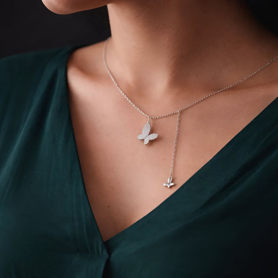 Butterfly necklace on a person wearing a green dress against a dark background