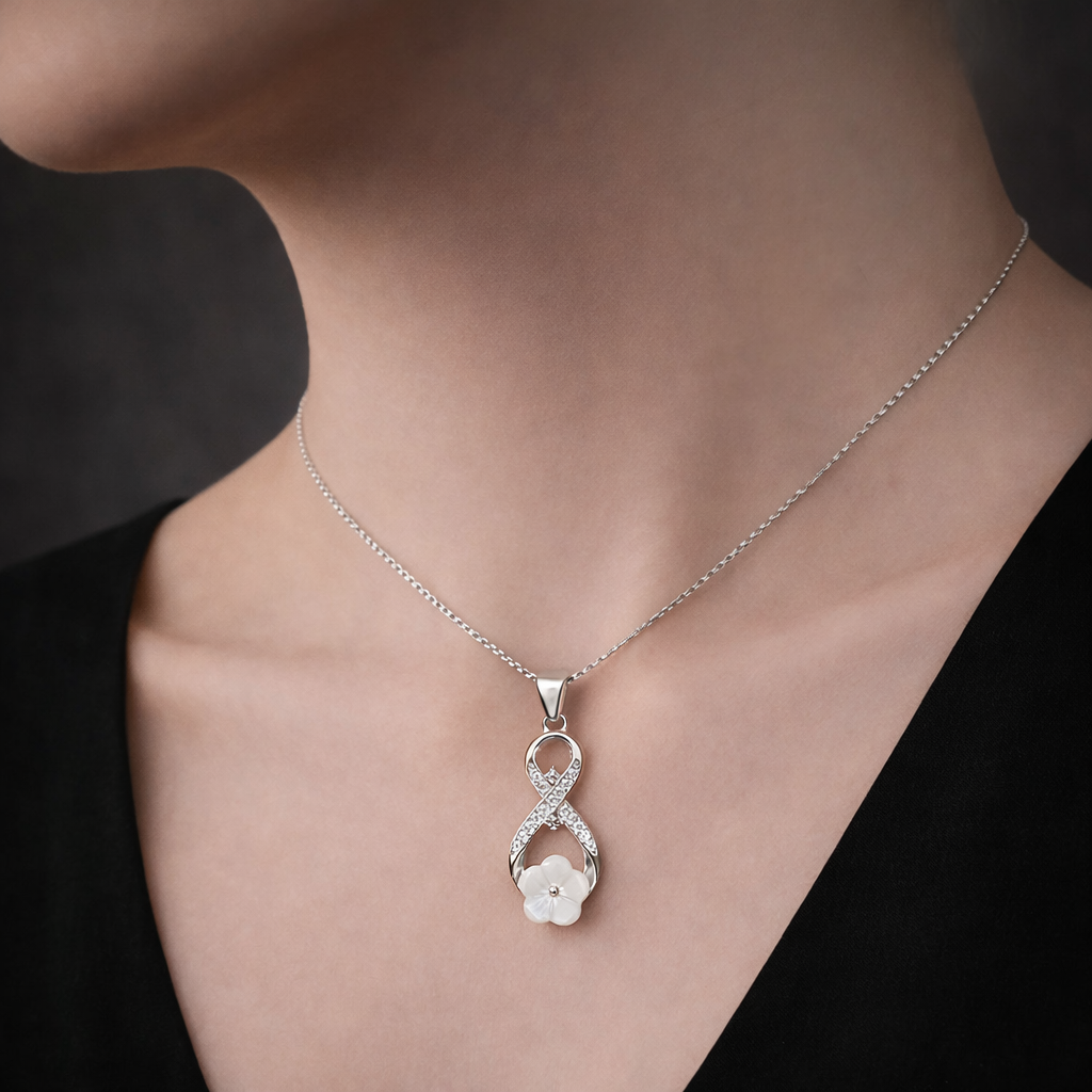 Silver necklace with a floral pendant on a person wearing a black top.