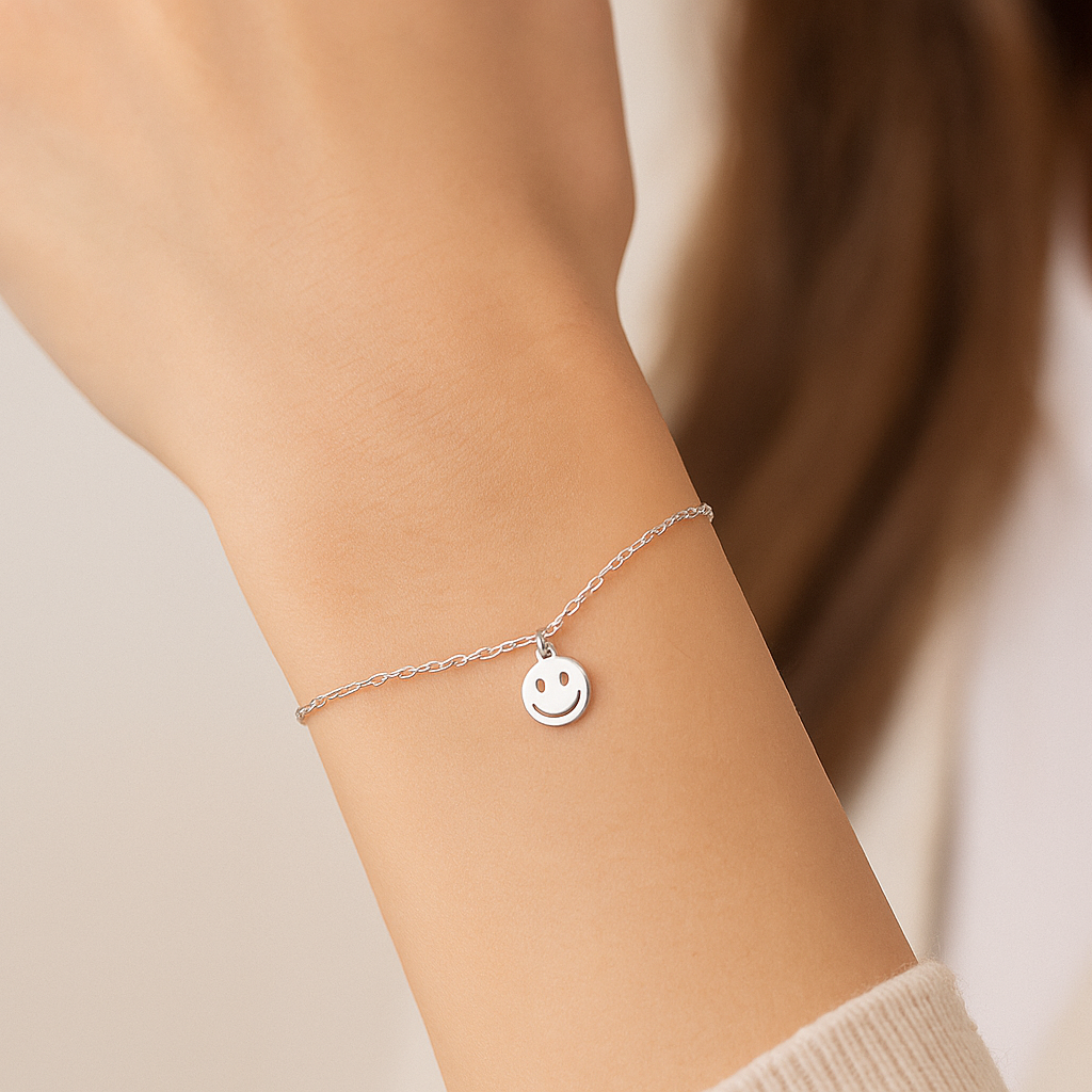 Silver bracelet with a heart charm on a wrist against a neutral background