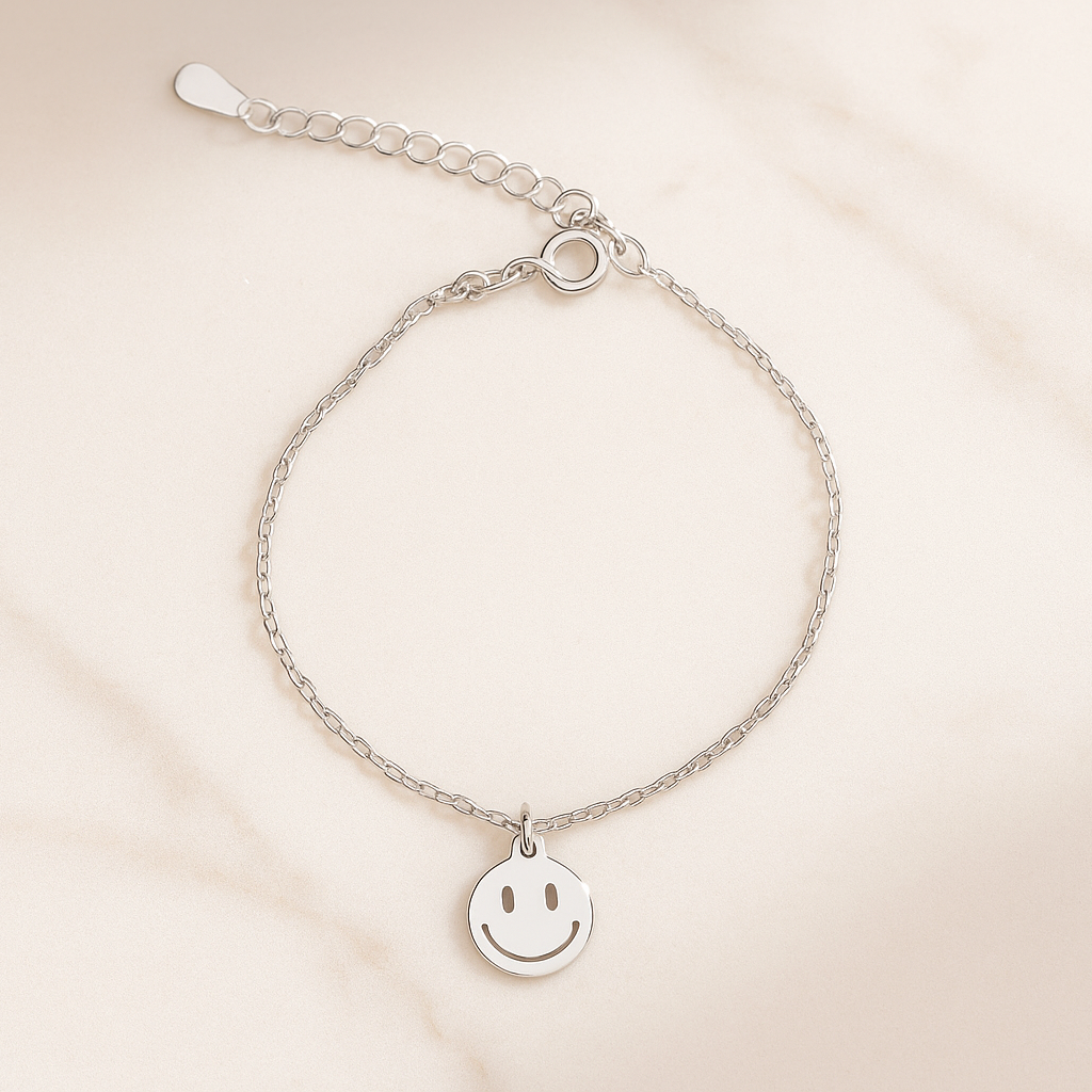 Silver bracelet with a smiley face charm on a beige background