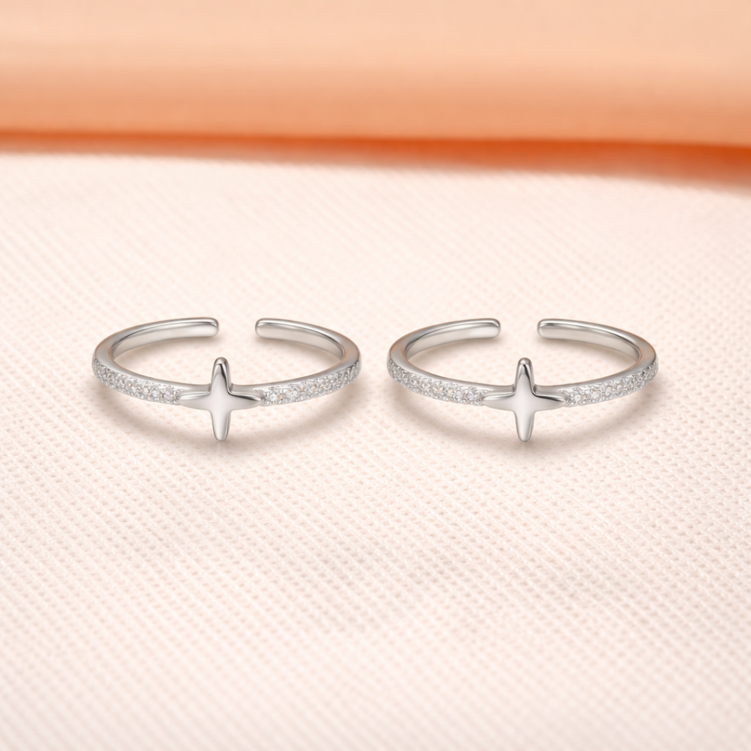 Two silver open nova star toe rings with star designs on a light pink background
