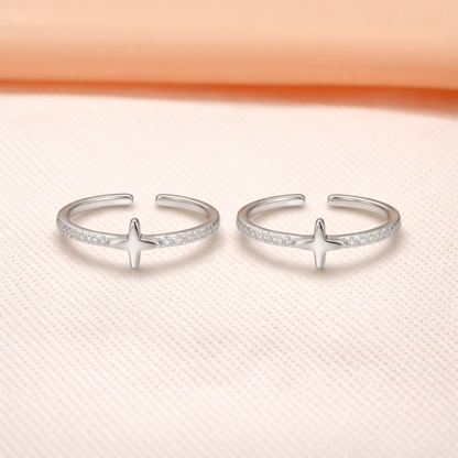 Two silver open nova star toe rings with star designs on a light pink background