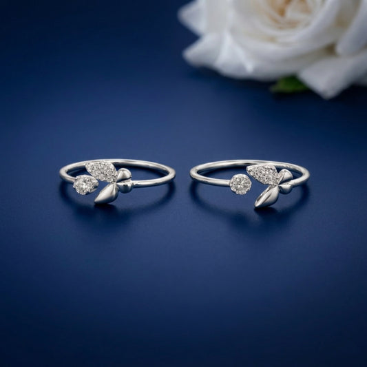 Two silver rings with butterfly  design of toe rings on a blue background with a white rose.