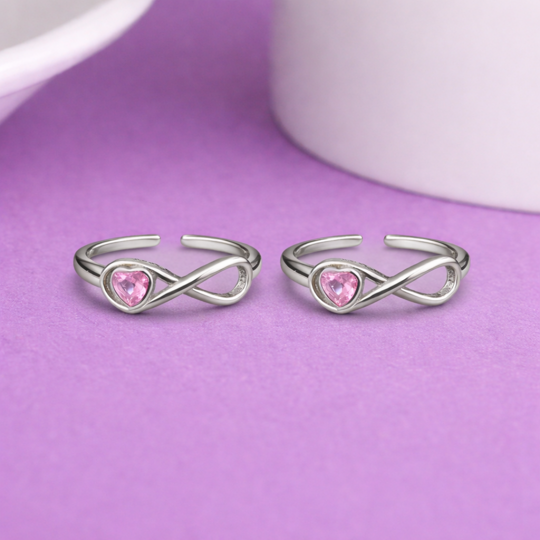 Silver rings with pink heart stones on a purple background