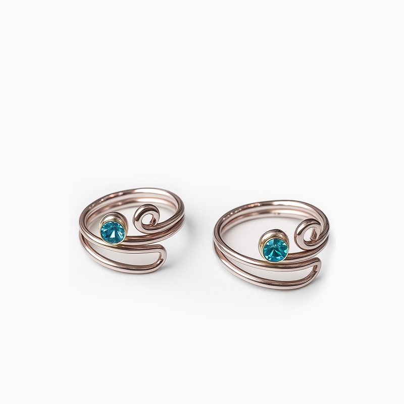 Two silver wire-wrapped toe rings with blue gemstones on a white background