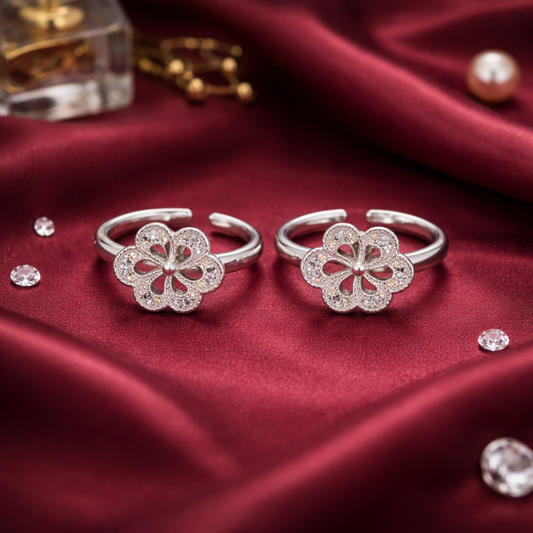 Two silver flower-shaped rings on a red fabric background with small crystals.