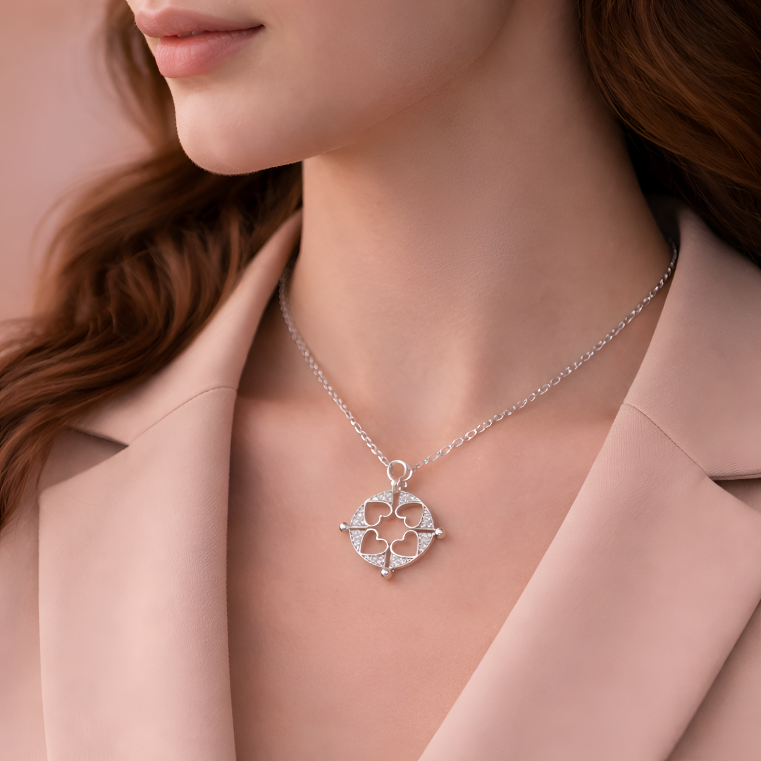 Silver necklace with a heart pendant worn by a person in a pink coat.