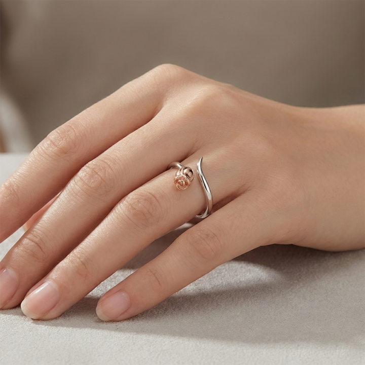 Hand wearing two rings on a neutral background