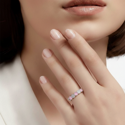Close-up of a hand wearing a pink and silver ring with a blurred background