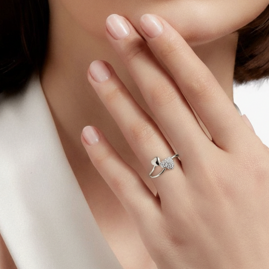 Close-up of a hand wearing a silver ring with a diamond on a neutral background