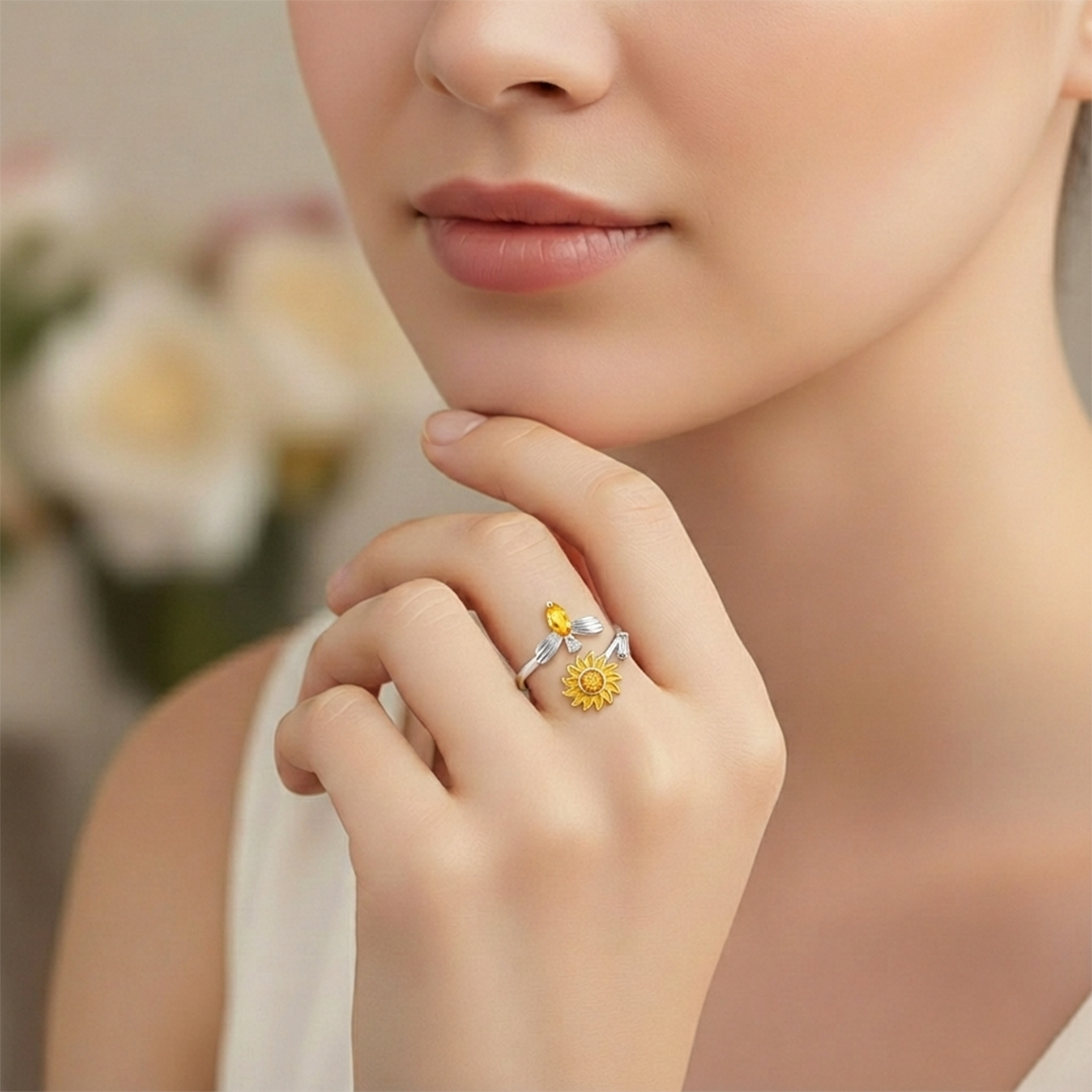Close-up of a hand wearing two rings with floral designs, against a blurred background.