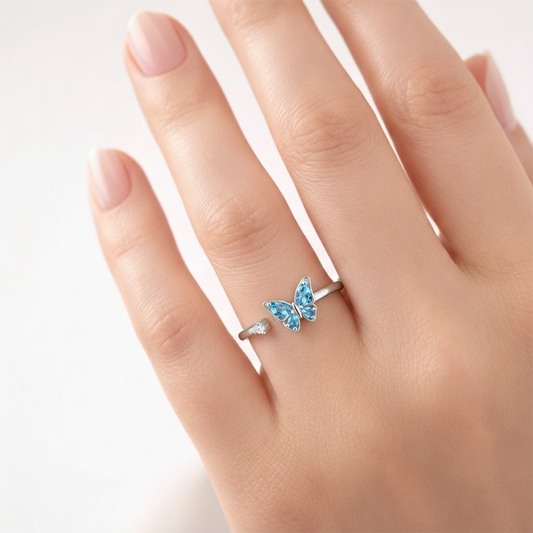 Butterfly-shaped ring with blue gemstones on a hand against a white background