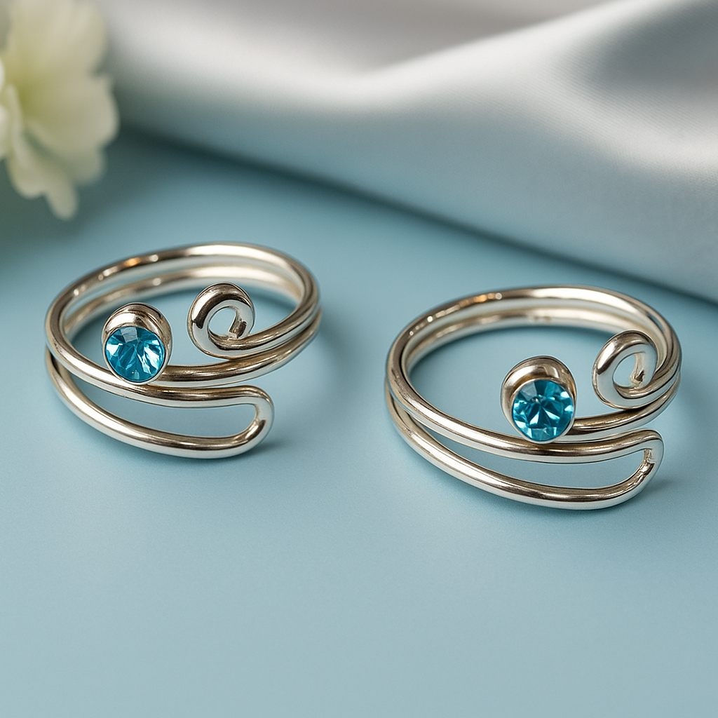 Two silver swirl tor rings with blue gemstones on a light blue background