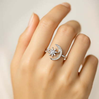 Silver ring with star and moon design on a hand against a neutral background