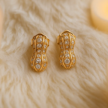 Gold earrings with diamond accents on a fur surface with candles in the background