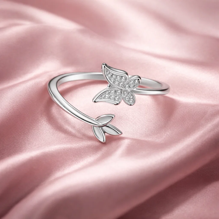 Silver butterfly ring on a pink satin background