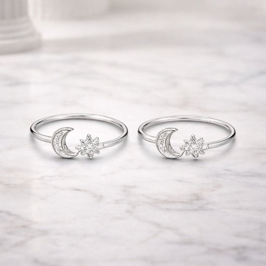 Pair of silver rings with moon and star designs on a marble surface
